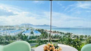 A balcony with a table and chairs, overlooking a beach and cityscape. - Seaview Cam Ranh (Bac Cam Ranh)