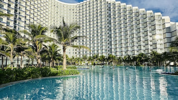 A large swimming pool surrounded by lush greenery and tall buildings. - Seaview Cam Ranh (Bac Cam Ranh)