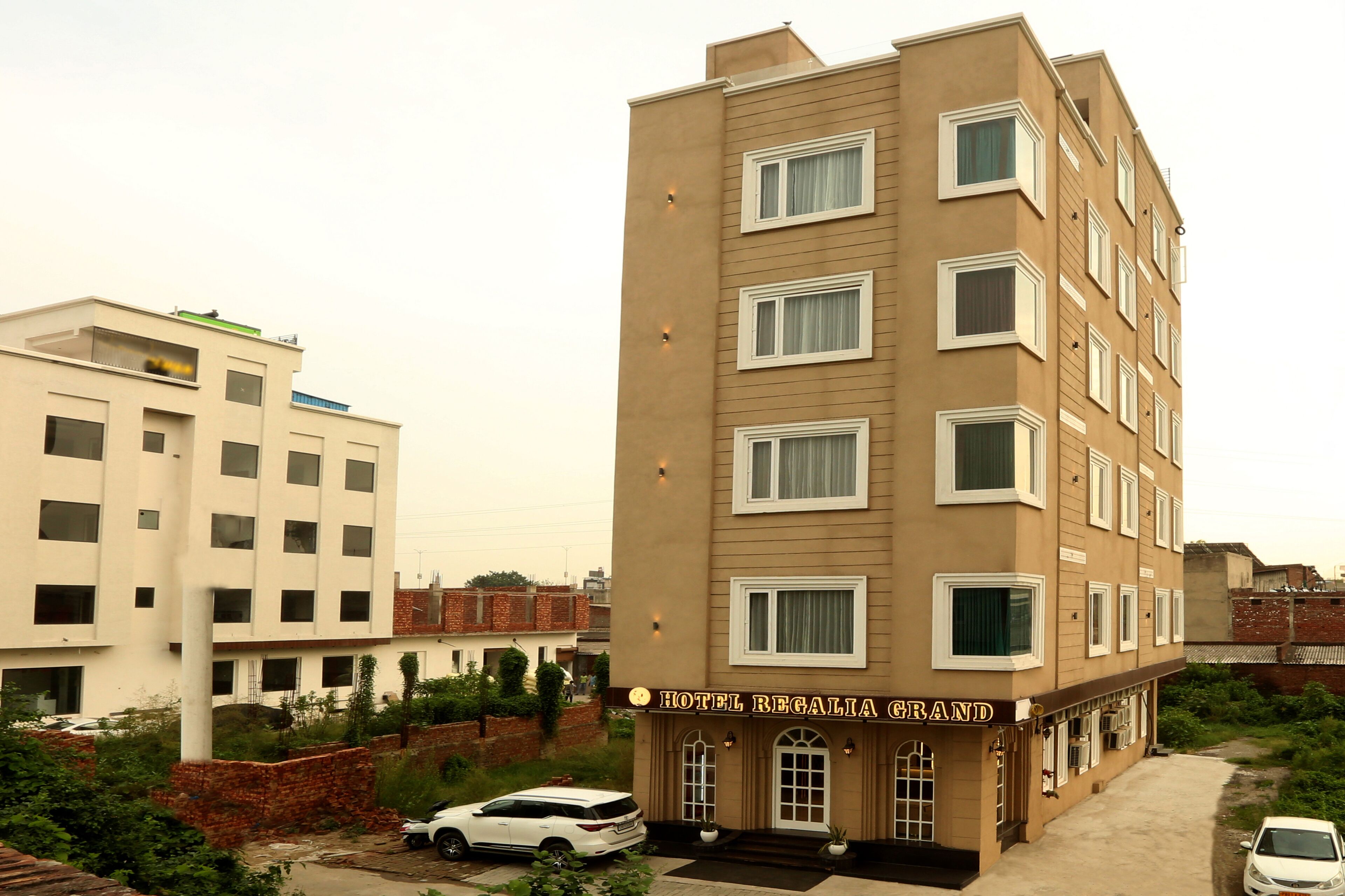 A multi-story hotel with a beige facade and a sign reading "Hotel Regalia Grand".