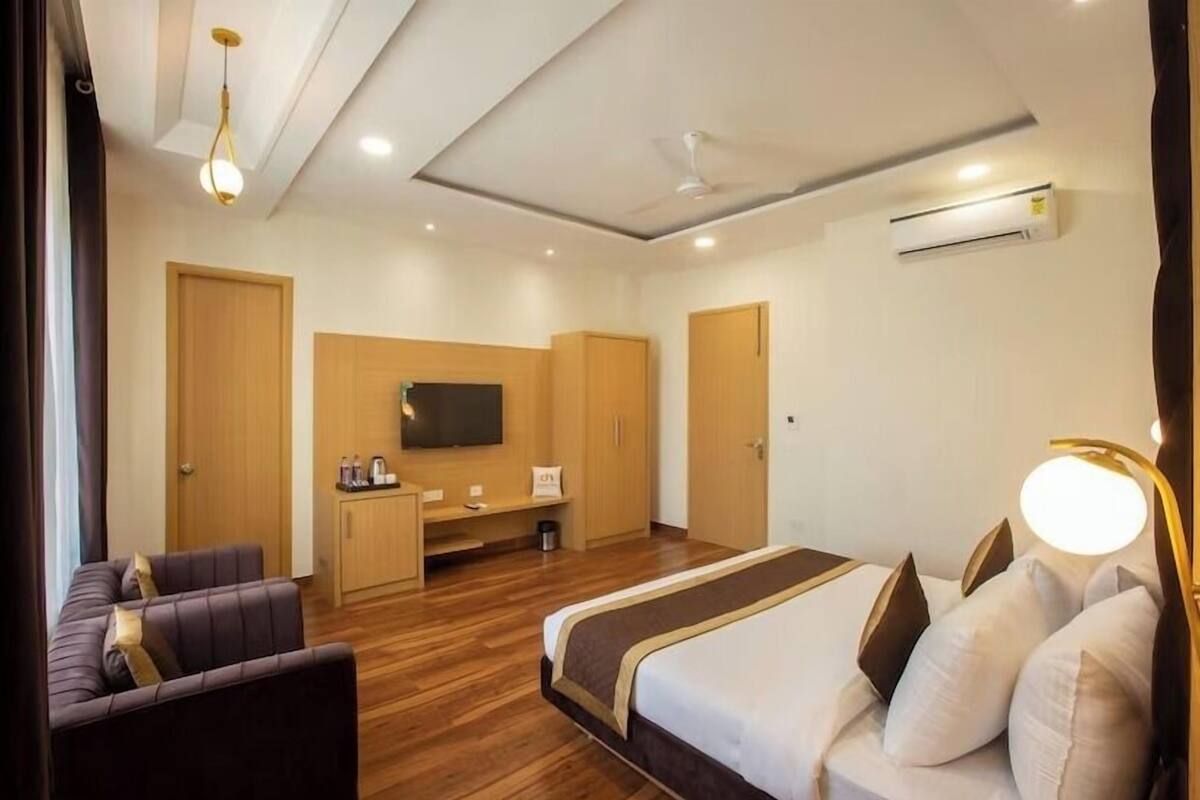 Ein Hotelzimmer mit Bett, Sofa, Fernseher und Schreibtisch.