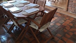 A dining area with a brick wall, wooden chairs, and a table set for four.