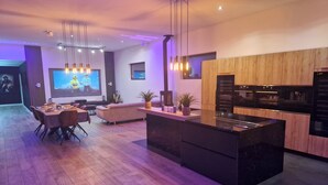 A modern kitchen with a central island, wooden cabinets, and built-in appliances.