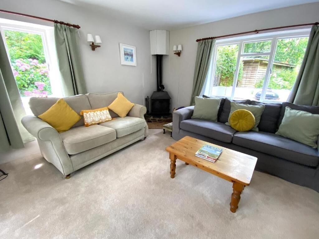 A living room with two sofas, a wooden coffee table, and a wood-burning stove.