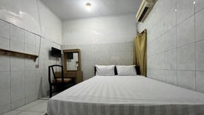 A bedroom with a bed, a chair, a wooden shelf, a television, and a mirror. - Hotel O Guest House Akbarrinna (Babulu)