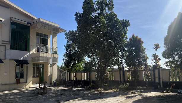 A building with a balcony, a gated entrance, and a paved courtyard. - Hotel O Guest House Akbarrinna (Babulu)