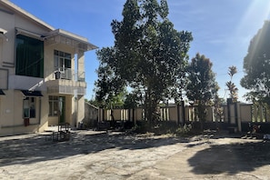 A building with a balcony, a gated entrance, and a paved courtyard. - Hotel O Guest House Akbarrinna (Babulu)