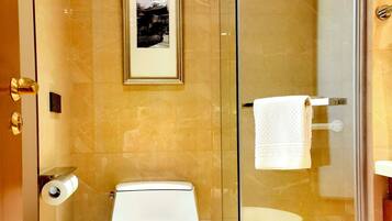 Ein modernes Badezimmer mit Toilette, einer Duschkabine und einem gerahmten Bild an der Wand.