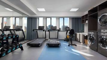 A modern gym with treadmills, dumbbells, and a washing machine.