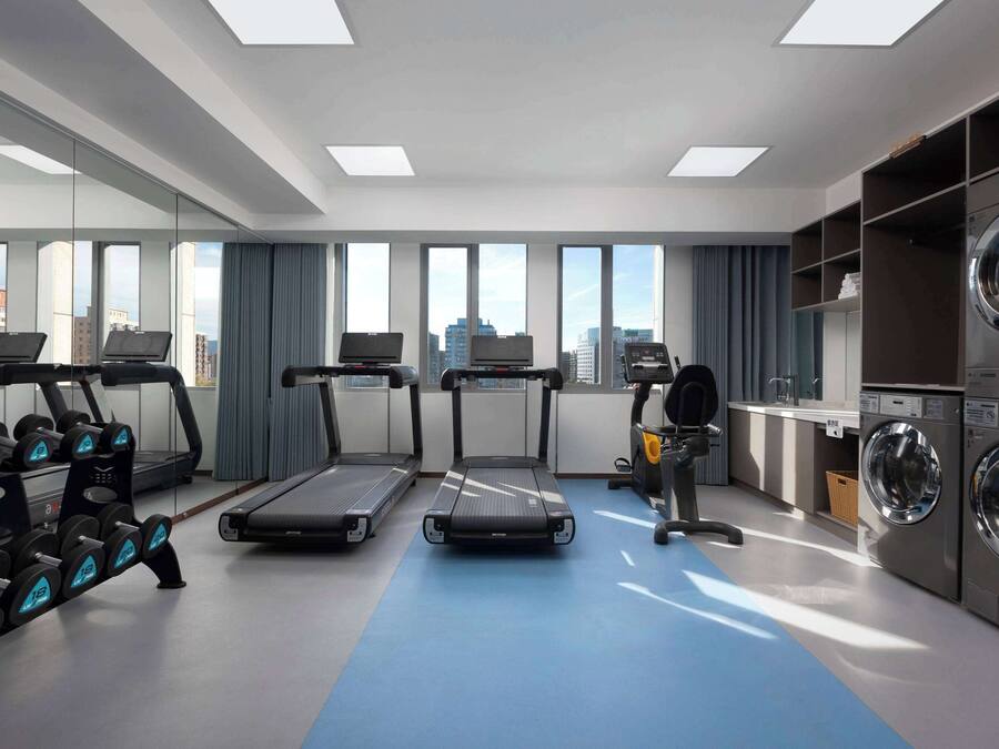 A modern gym with treadmills, dumbbells, and a washing machine.