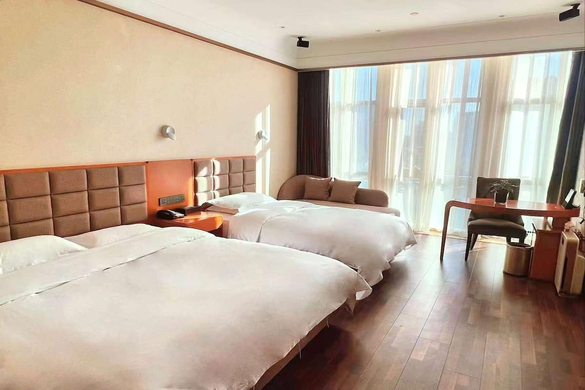 Hotellihuone, jossa on kaksi sänkyä, työpöytä ja tuoli.