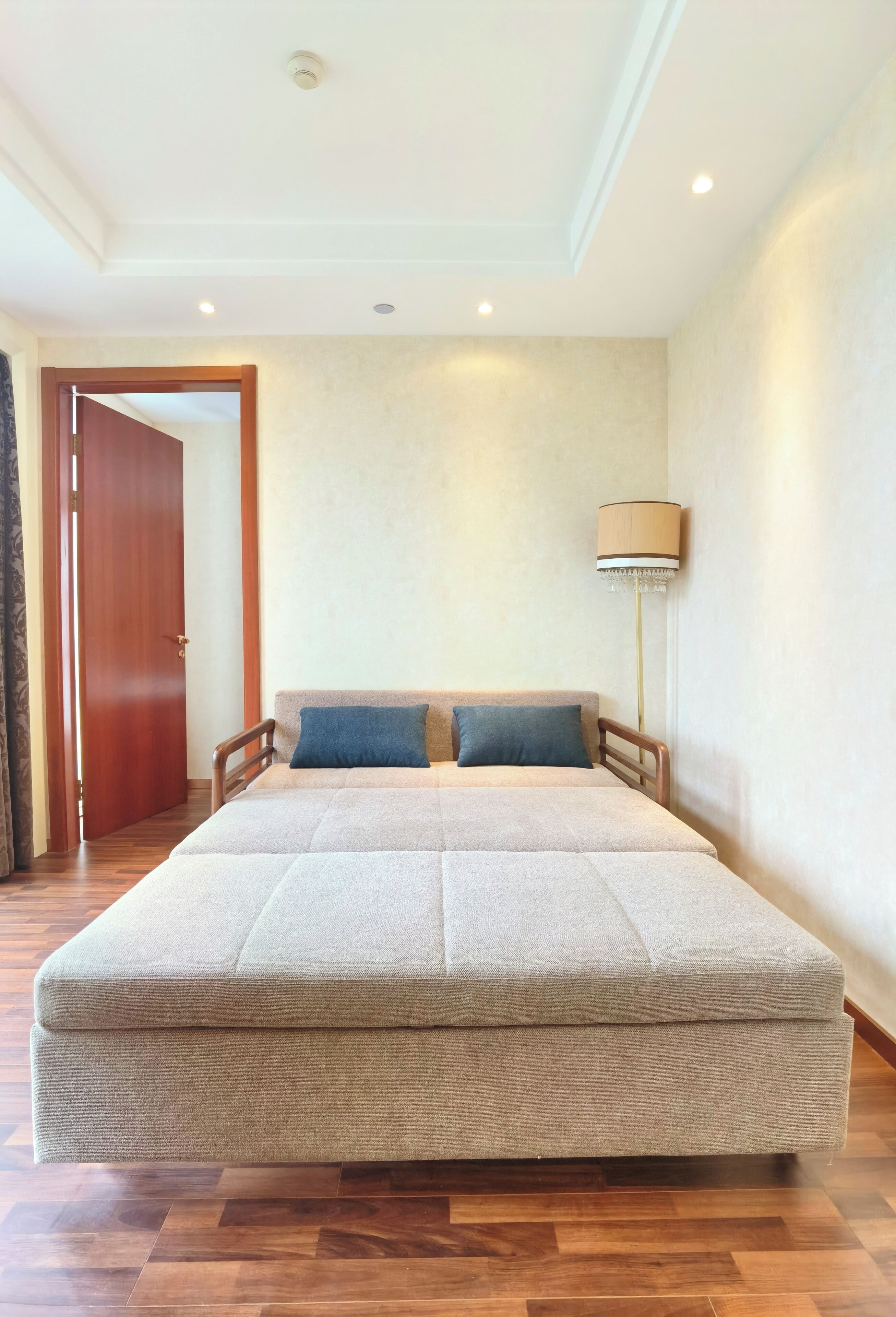 Un dormitorio espacioso con una cama grande, suelo de madera y una puerta que da a otra habitación.