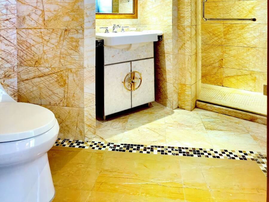 A bathroom with a marble wall, a sink, a toilet, and a shower area.