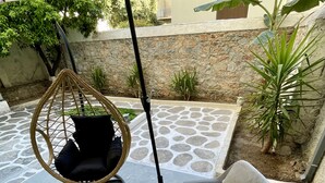 A patio area with a hanging chair, a small table, and two chairs. - Central Studio Flat with Garden (Volos)