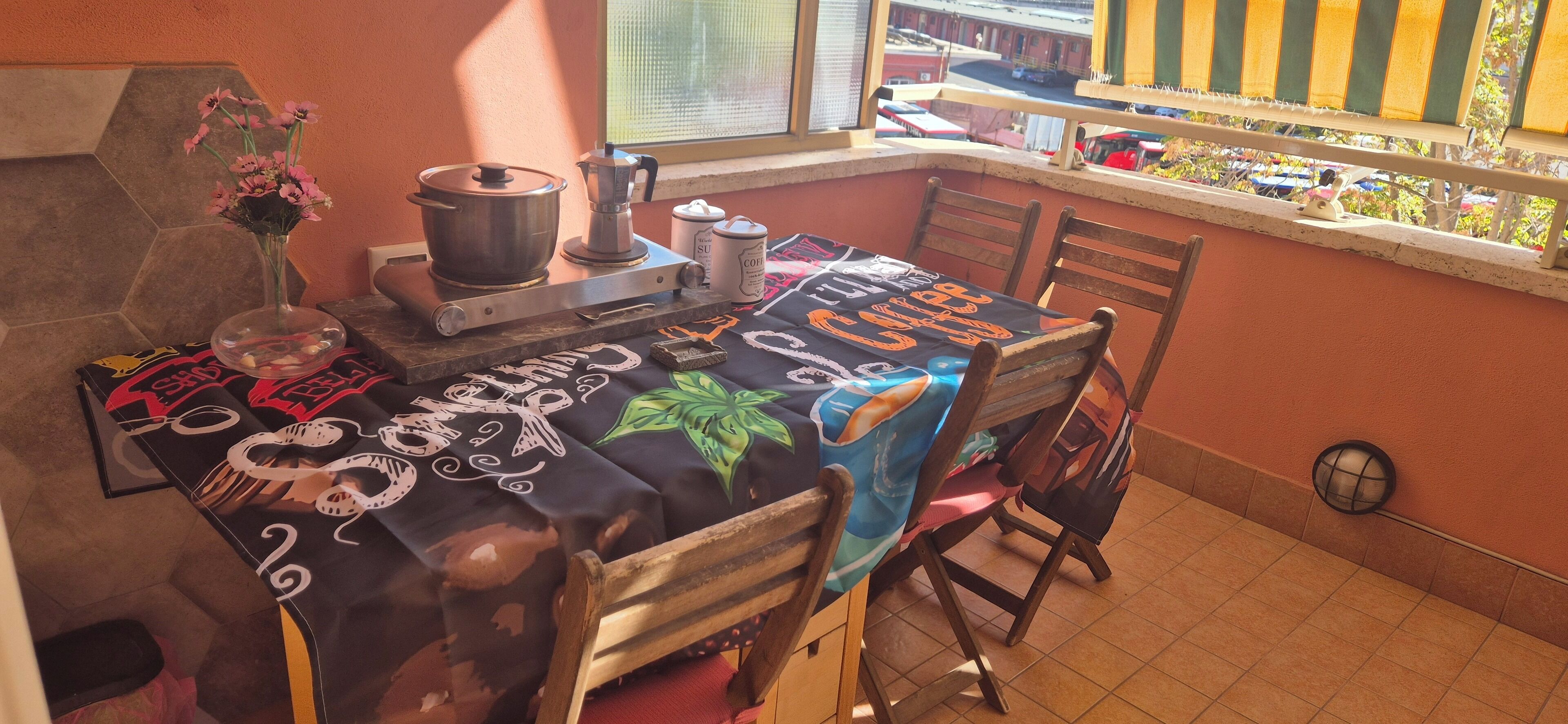 A kitchen with a stove, a coffee machine, and a table with a coffee-themed tablecloth.