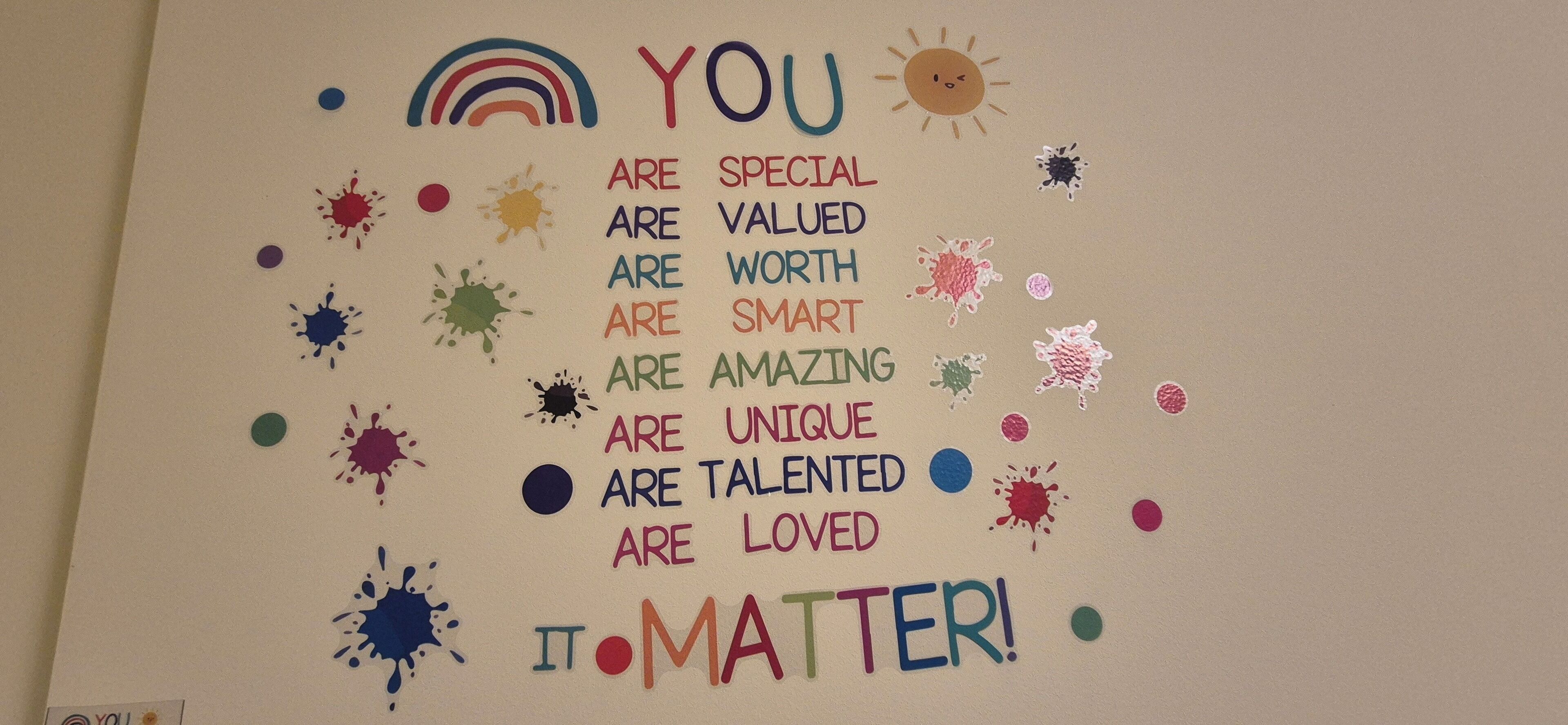 Um cartaz motivacional com respingos de cores vibrantes e texto numa parede.