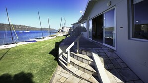 A house with a stone staircase leading to a deck overlooking a marina with boats. - Sandbaai Villa Langebaan 7 sleeper (Langebaan)
