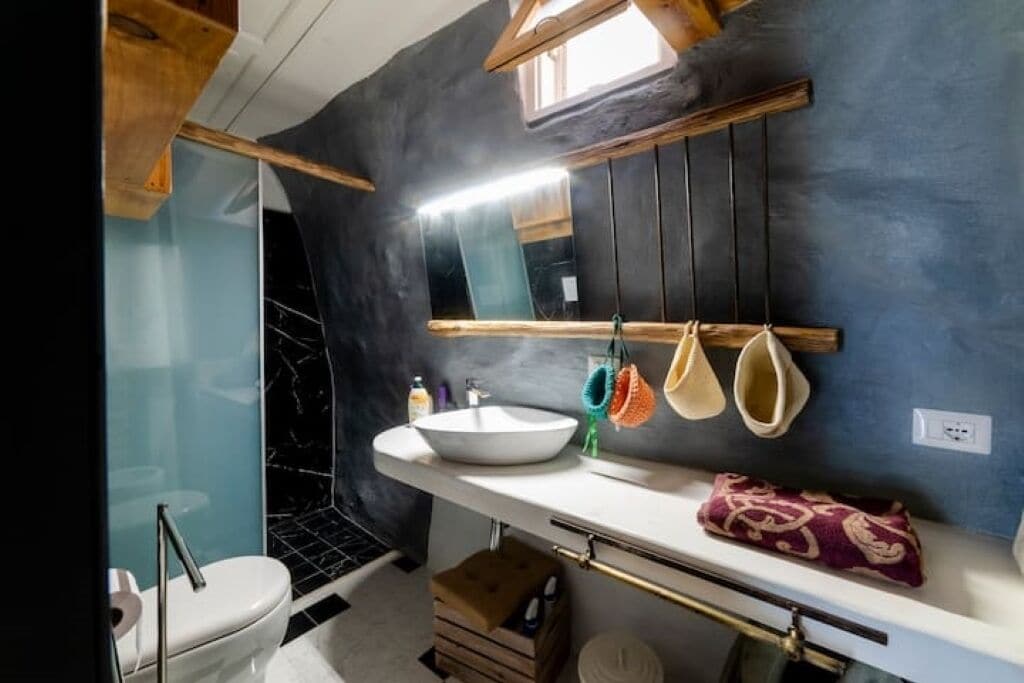 Un baño moderno con un espejo grande, un lavabo blanco y un inodoro.