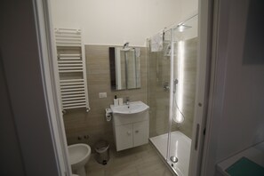 A modern bathroom with a toilet, sink, and glass-enclosed shower.