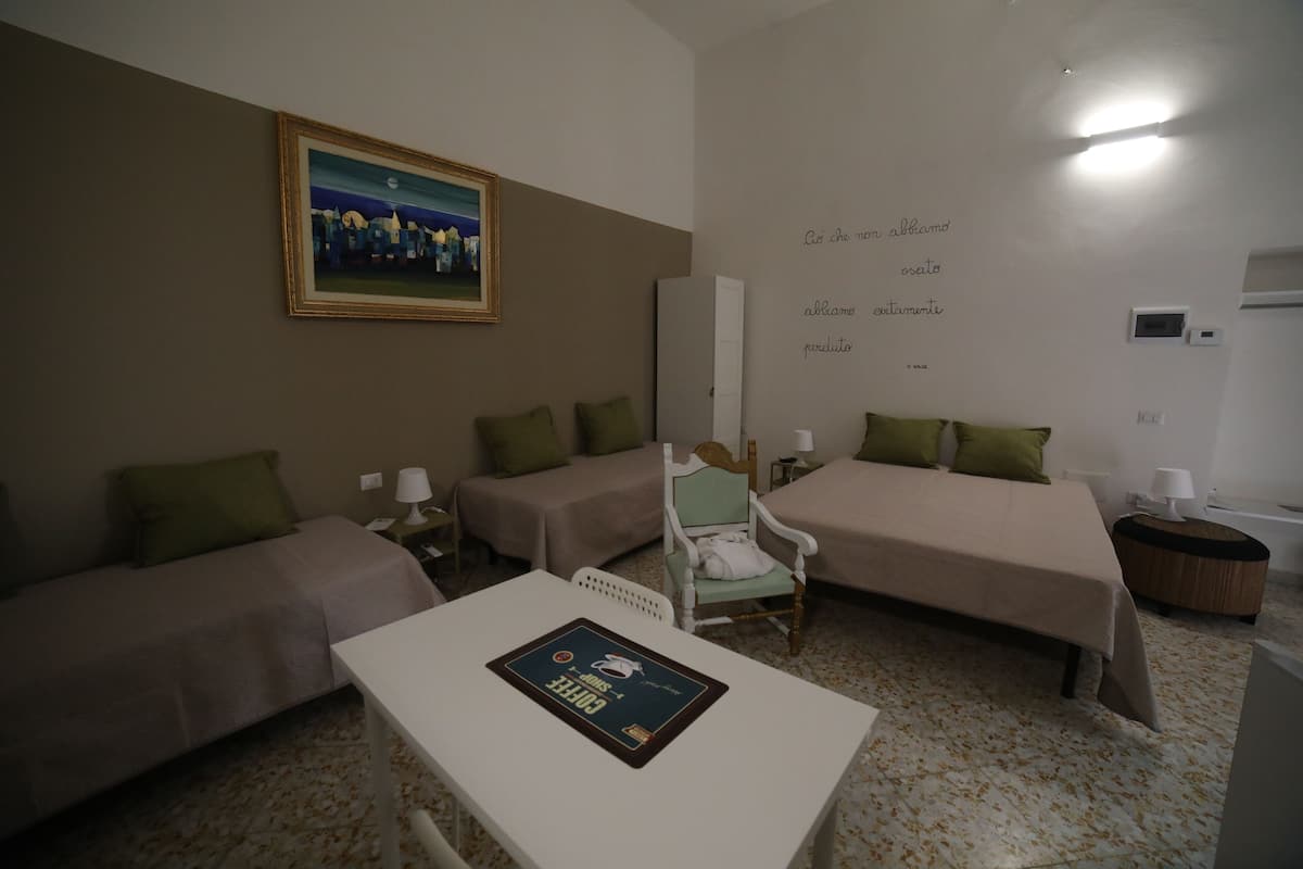 A hotel room with two single beds, a sofa, a table, and a painting on the wall.