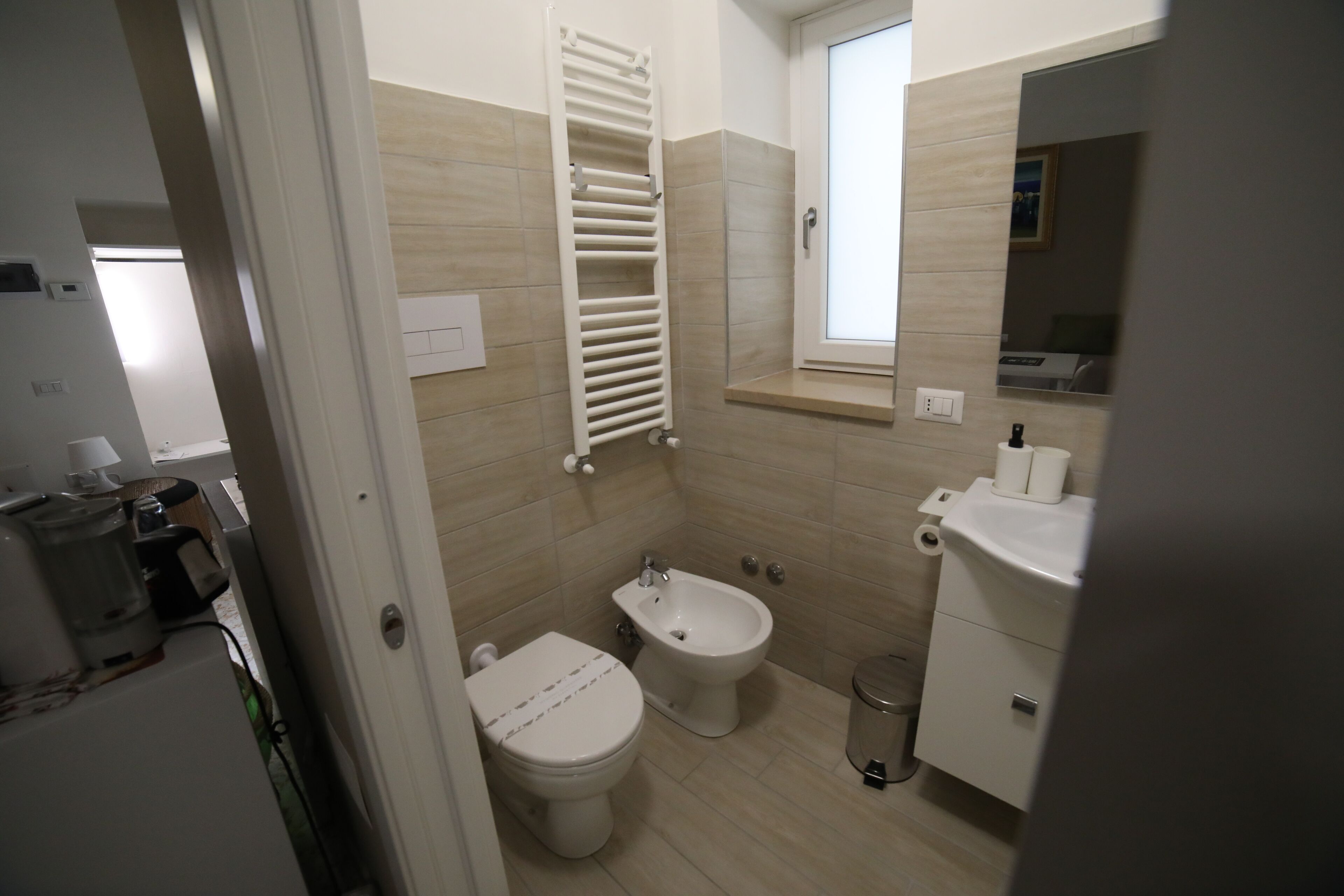 Une salle de bain comprenant des toilettes, un bidet, un lavabo et un porte-serviettes.