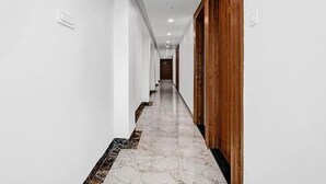 A long, narrow hallway with white walls and a marble floor. - Hotel Silvotel Stays (Indore)