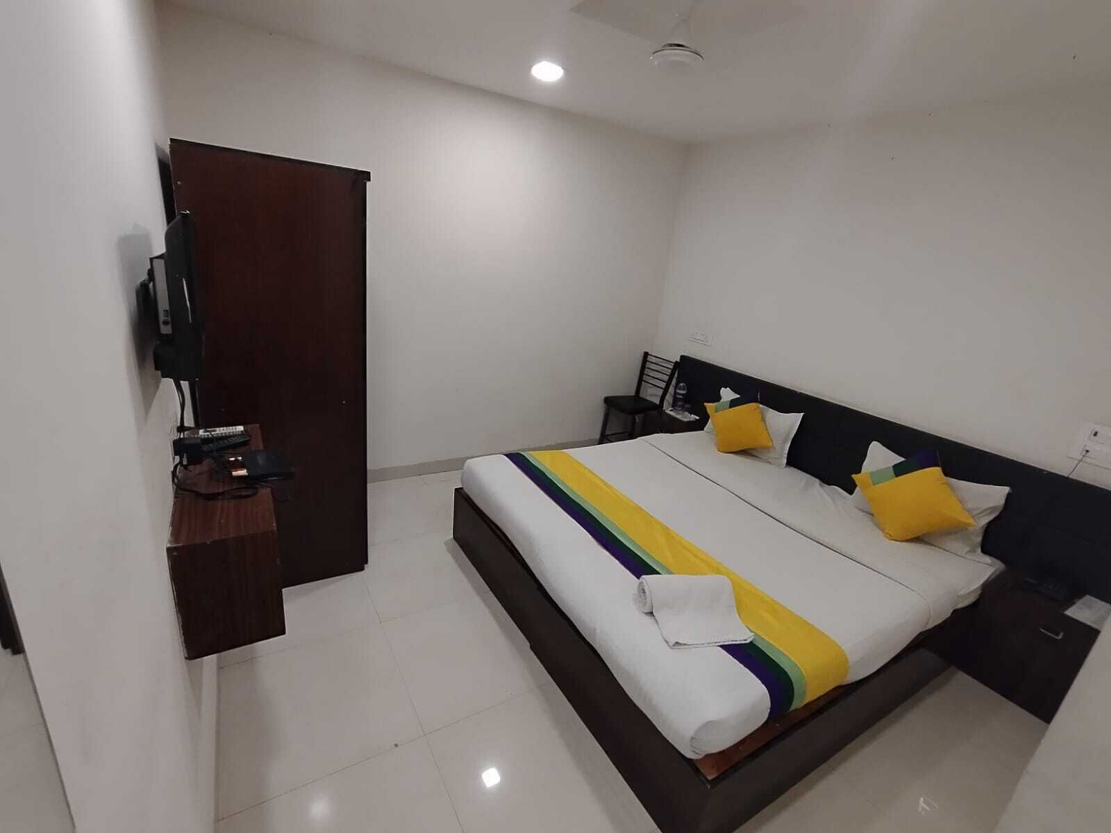 Ein Hotelzimmer mit Bett, Fernseher, Schreibtisch und Stuhl.