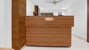A reception desk with a 'RECEPTION' sign, a ceiling fan, and a clock on the wall. - Hotel Silvotel Stays (Indore)