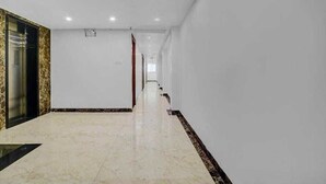 A long, narrow hallway with white walls and a tiled floor. - Hotel Silvotel Stays (Indore)