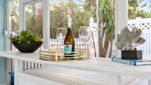A white table with a bottle of Asolo Roséccolo wine, two glasses, a black bowl with plants, and a decorative sculpture. - Exclusive complex - Private Heated Pool - 100 Steps to Beach - Village 5 minute walk (Siesta Key)