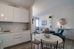 A modern kitchen with white cabinets, a round dining table with chairs, and a small island with a bowl.