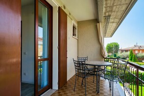 A balcony with a checkered floor, a table, and chairs.