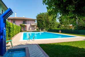 A swimming pool with a tiled deck, a small diving area, and a lifebuoy.