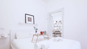 Una habitación de hotel moderna con una cama bien hecha, una pequeña mesita de madera con una bandeja y un cuadro enmarcado en la pared.