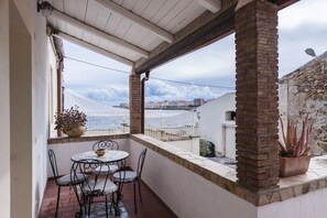 Un balcone con tavolo e sedie, una pianta in vaso e vista sul mare e sugli edifici.