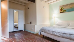 A bedroom with a bed, a wardrobe, a painting on the wall, and a tiled floor. - Casa Florus by Wonderful Italy (Syracuse)