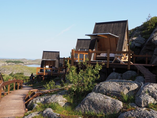 A wooden cabin with a deck, overlooking a lake and hills. - BaseCamp Vega (Vega)