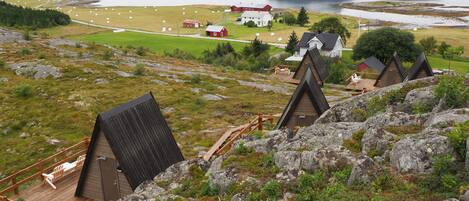 A mountainous area with several wooden cabins and a large house with a red roof.