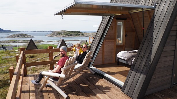 Une terrasse en bois avec un toit incliné donnant sur une étendue d’eau.