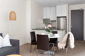 A compact living space with a dining area, kitchenette, and a grey sofa.