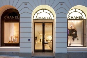 Una tienda Chanel con tres entradas arqueadas, cada una mostrando maniquíes en el escaparate.
