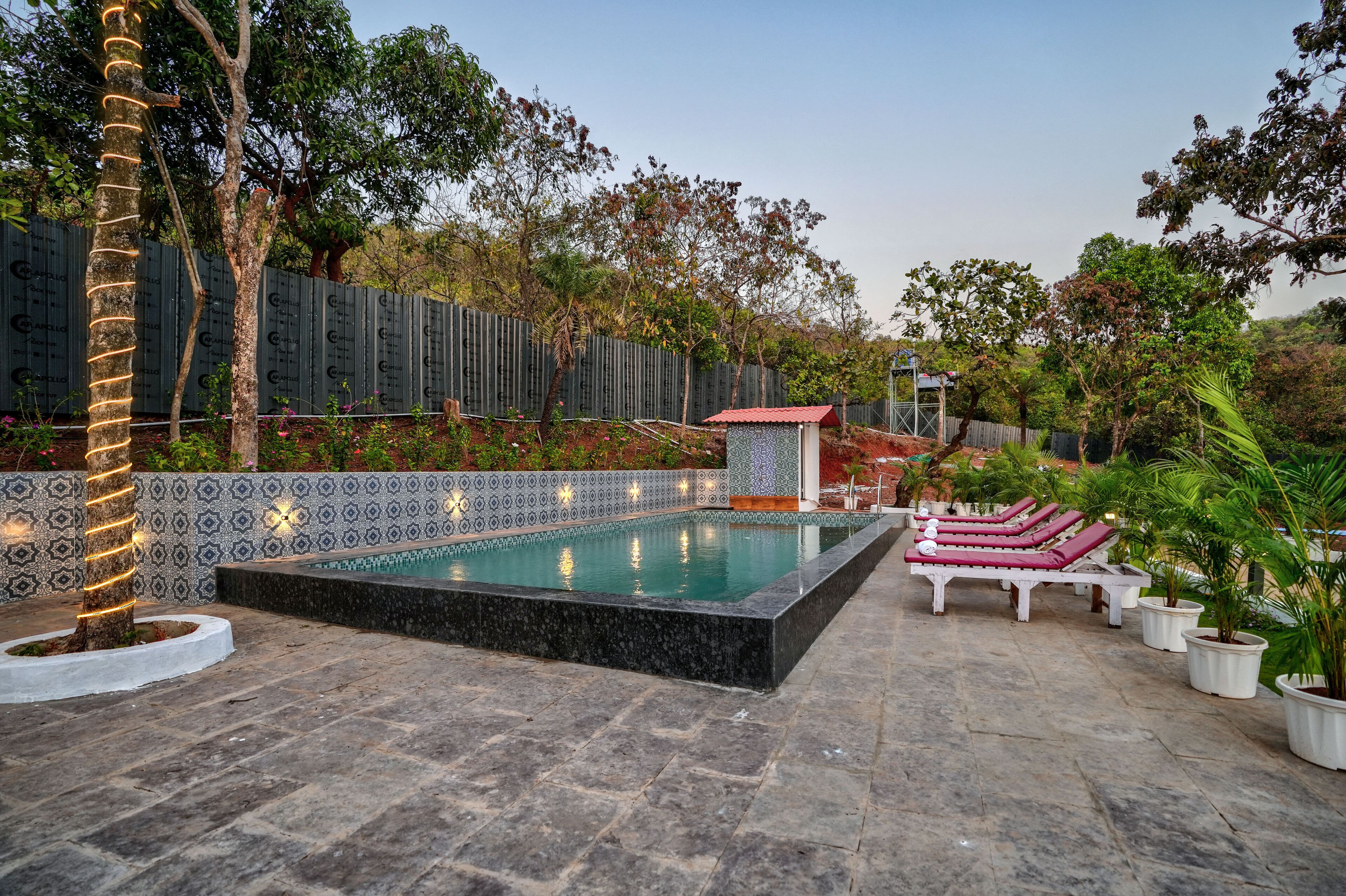 Un espace piscine doté d’une terrasse carrelée, de chaises longues et de plantes en pot.