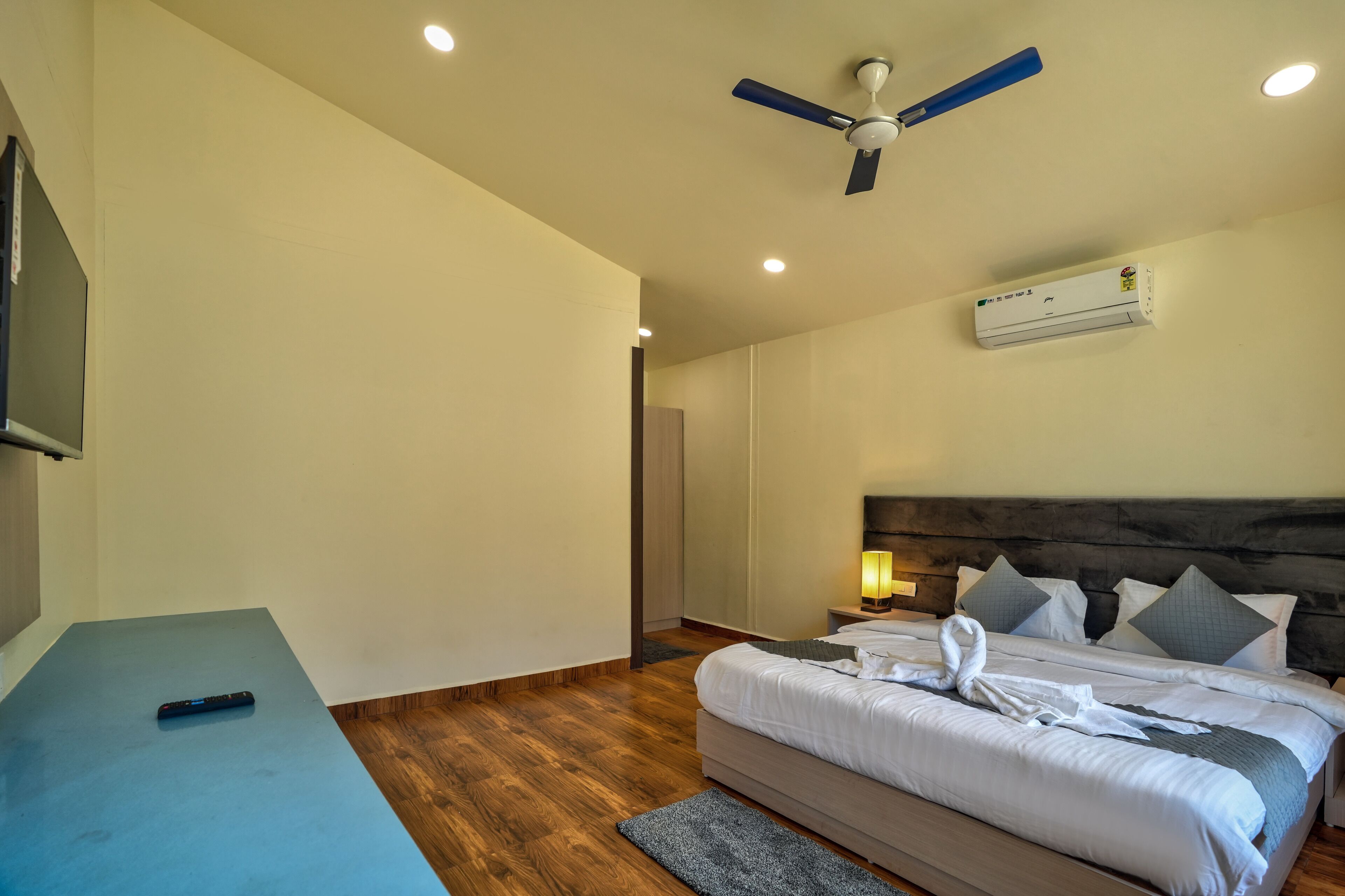 Een hotelkamer met een bed, een plafondventilator, een airconditioner, een bedlampje en een flatscreen televisie.