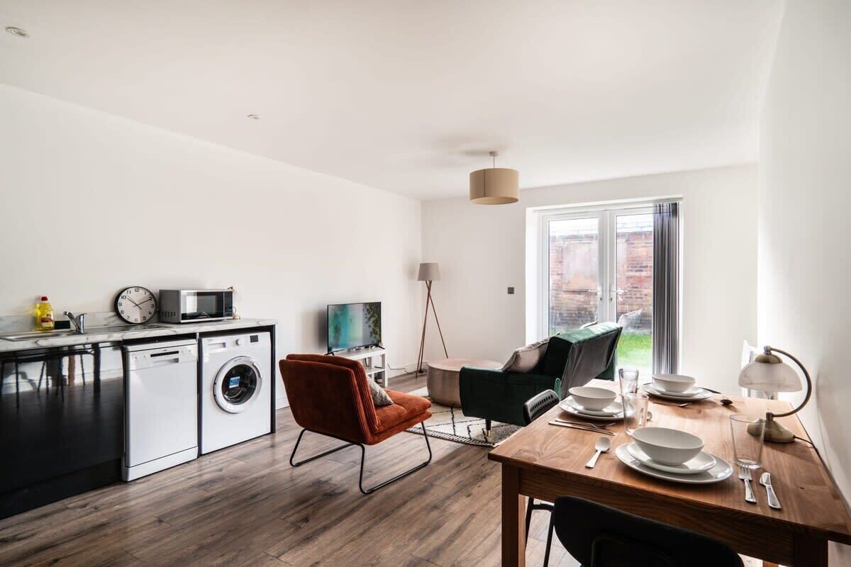 A modern kitchen with a washing machine, microwave, and a dining area with a table set for two.