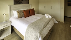 Une chambre d’hôtel avec un lit, une table de chevet, une armoire et un tableau au mur.