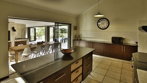 Une cuisine moderne dotée d’un grand îlot central, de meubles de rangement en bois foncé et d’un luminaire suspendu.