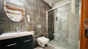 Un baño moderno con lavamanos, inodoro y ducha con paredes de vidrio.