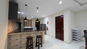 A kitchen with a brick backsplash, two pendant lights, a refrigerator, and a wooden door. - Impeccable 3-bed Villa in Anse Boileau! (Mahé Island)