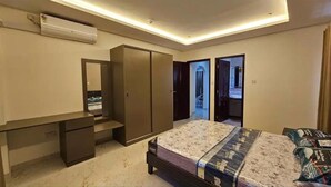 A bedroom with a bed, a desk, a wardrobe, and an air conditioning unit. - Impeccable 3-bed Villa in Anse Boileau! (Mahé Island)