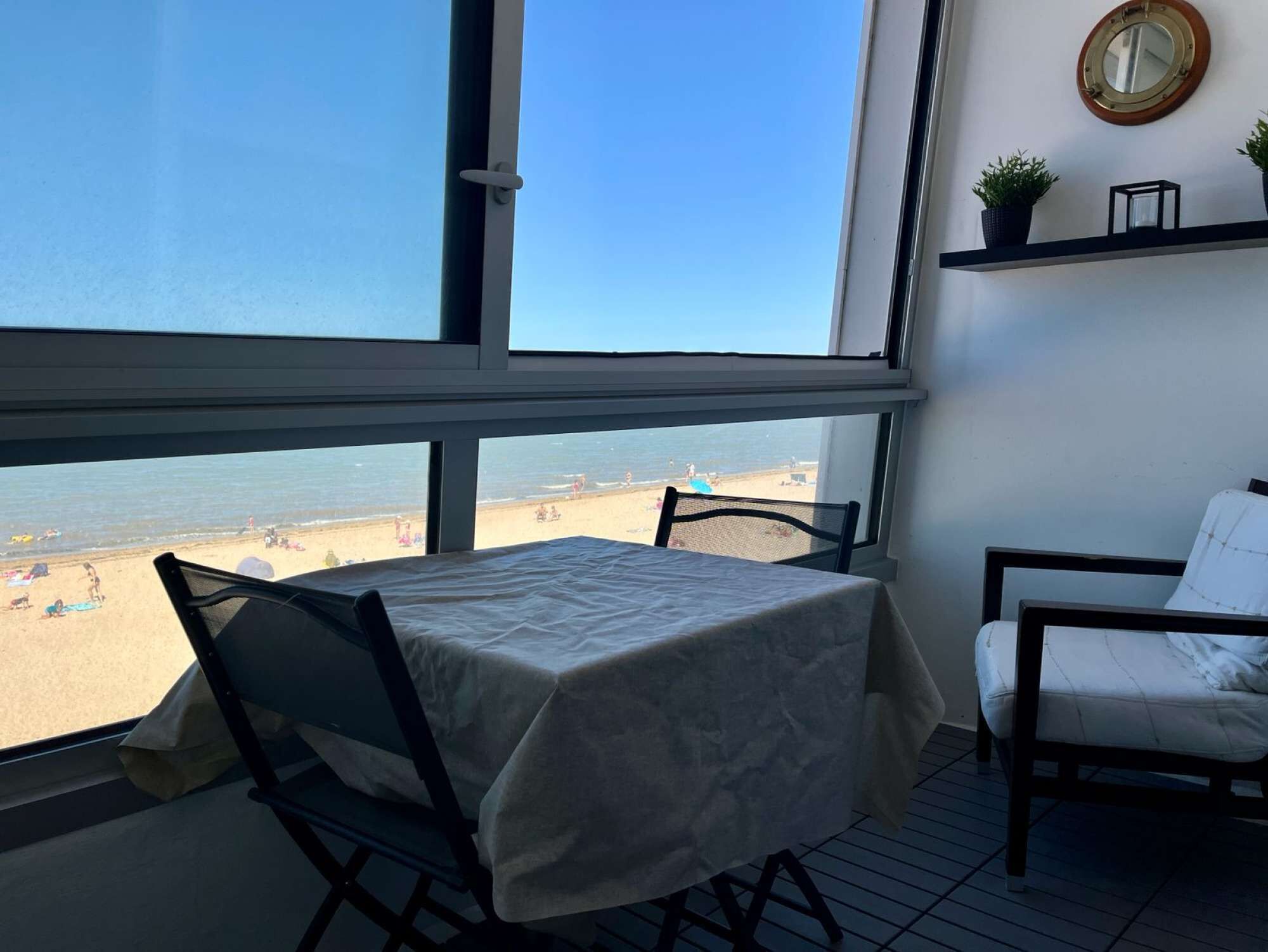 Un balcon avec une table et des chaises, donnant sur une plage.