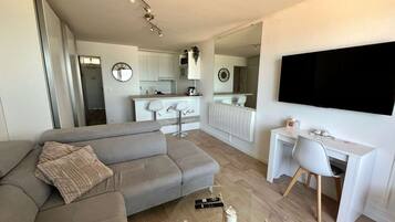 Un salon moderne avec un canapé gris, une table basse et un téléviseur fixé au mur.